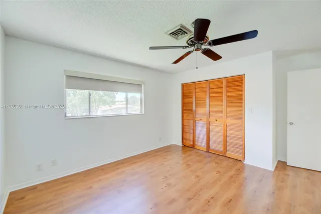 a view of empty room with wooden floor and ceiling fan