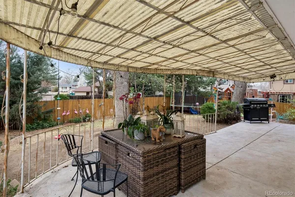 a view of a patio with a table and chairs under an umbrella with a barbeque