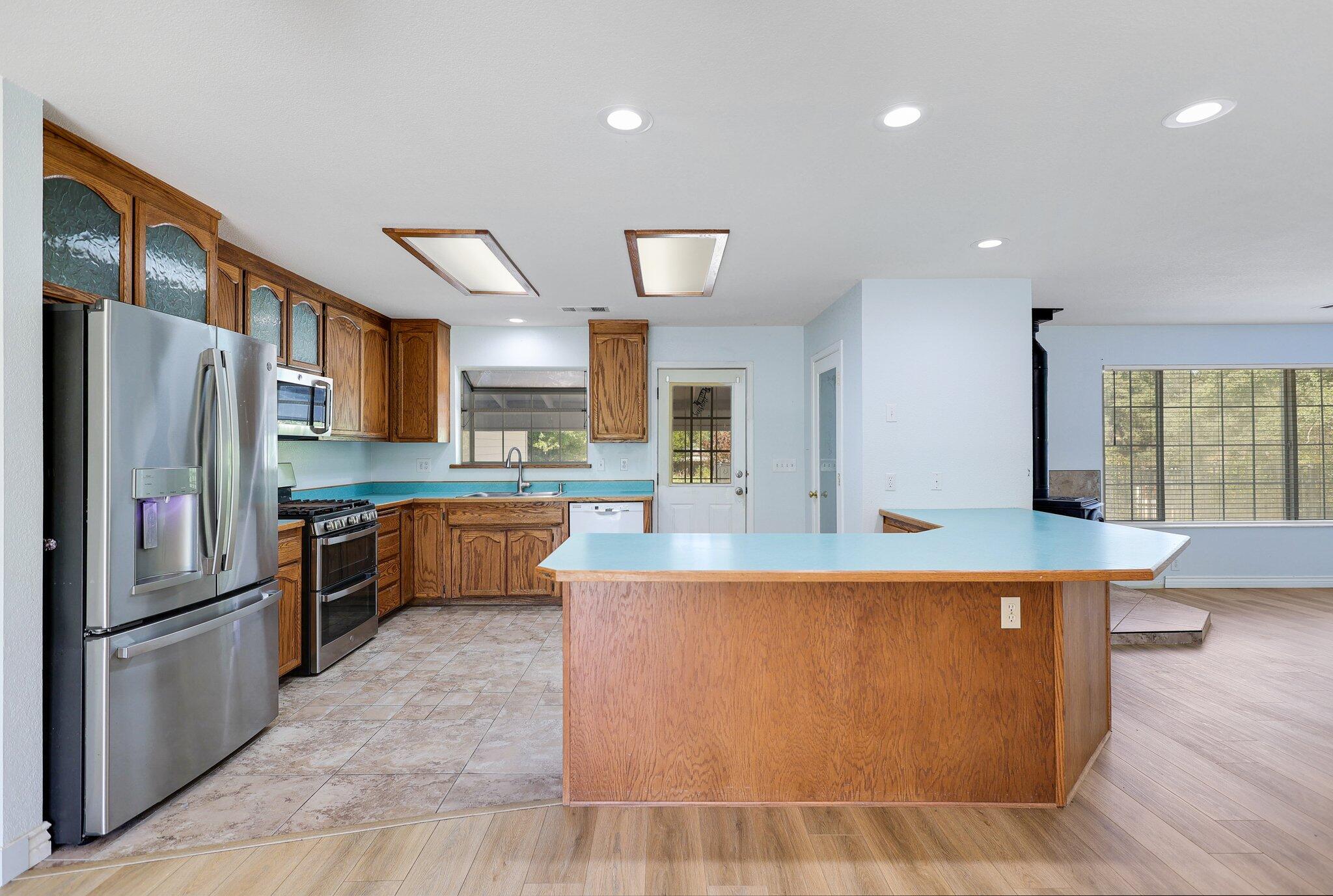 20727 Old Alturas Road Redding, CA 96003 - Photo 11 of 32 a large kitchen with stainless steel appliances kitchen island granite countertop a refrigerator a stove a sink a oven with a dining table and chairs