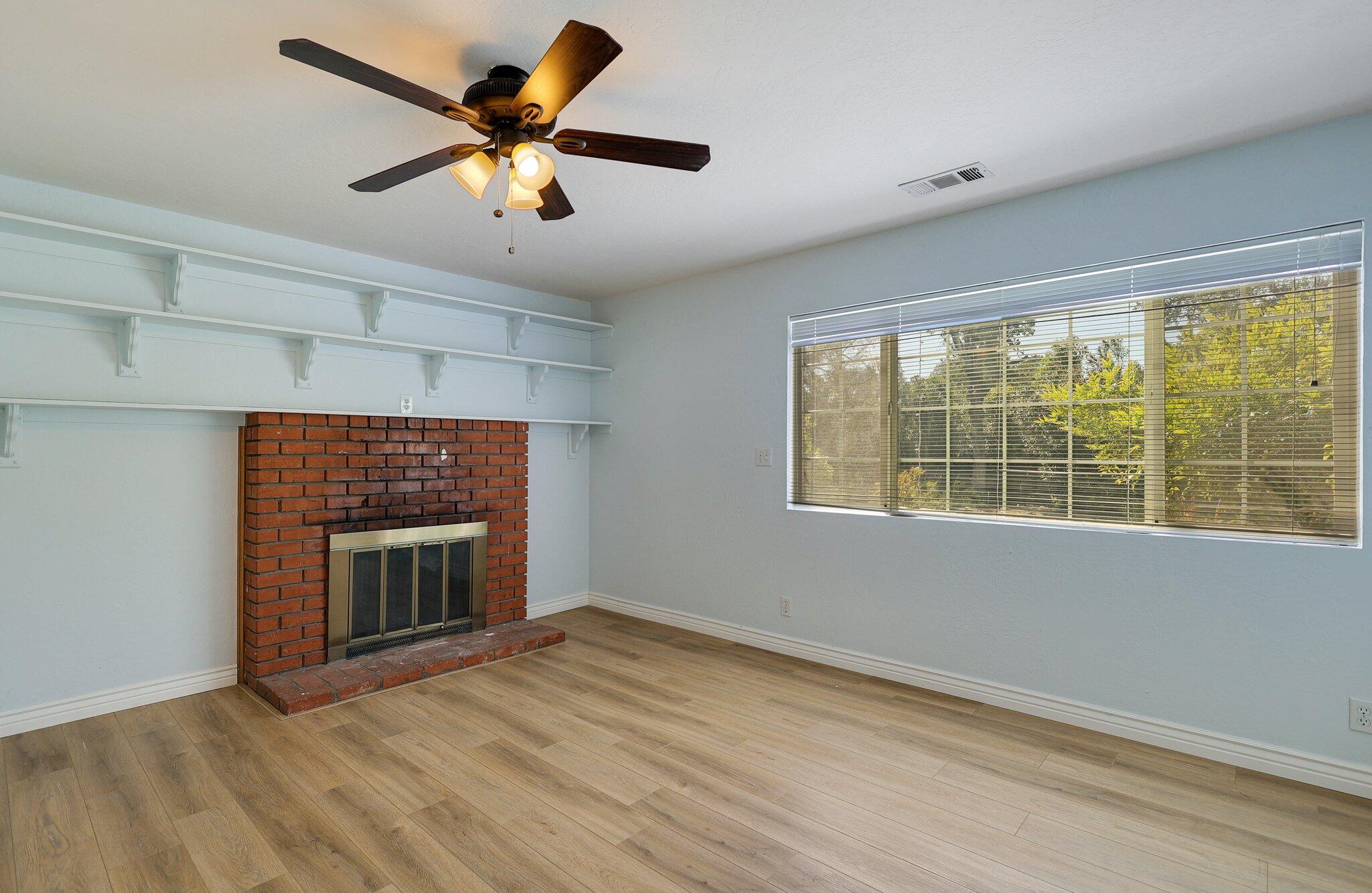 20727 Old Alturas Road Redding, CA 96003 - Photo 13 of 32 a view of an empty room with a fireplace and a window