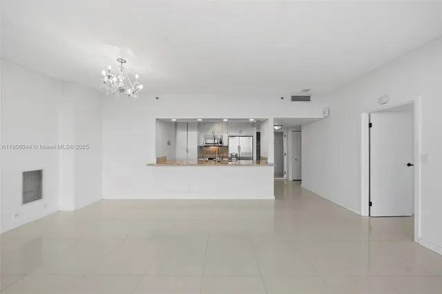 a view of a hallway with kitchen and chandelier