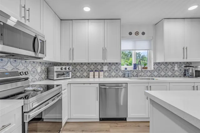 a kitchen with stainless steel appliances granite countertop a stove a sink and a microwave