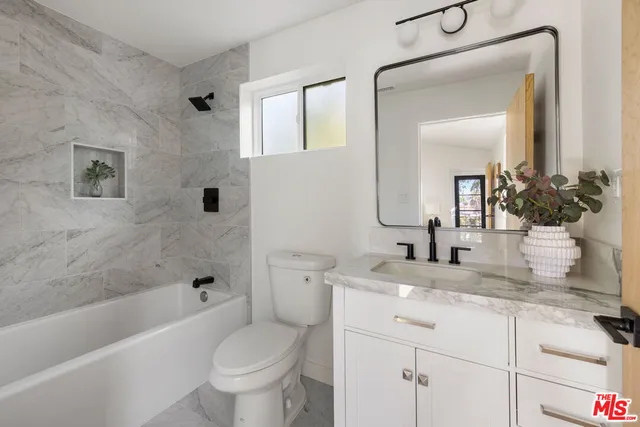 a bathroom with a granite countertop toilet a sink and a bathtub