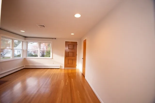 a view of an empty room with wooden floor and a window