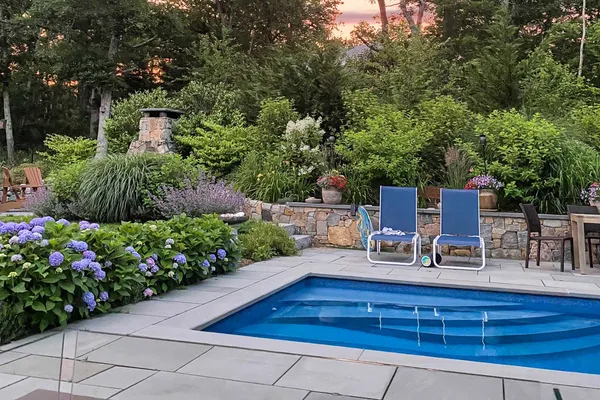 a view of backyard with seating space and trees in the background