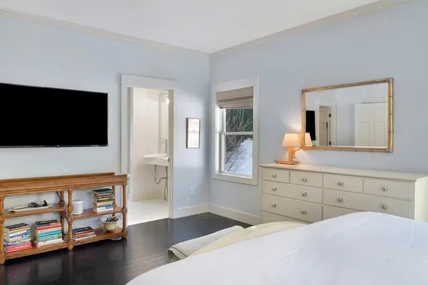 a bedroom with a bed and a flat tv screen on dresser
