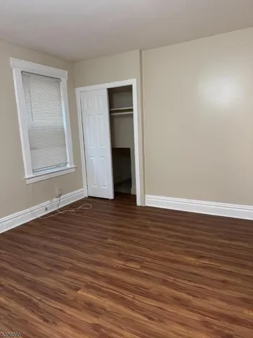 a view of an empty room with wooden floor and closet