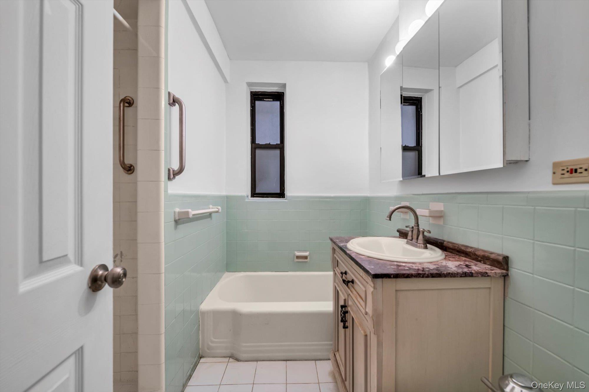123-35 82nd Road, Unit 4H Queens, NY 11415 - Photo 11 of 15 Bathroom featuring vanity, tile walls, a wainscoted wall, a garden tub, and light tile patterned floors