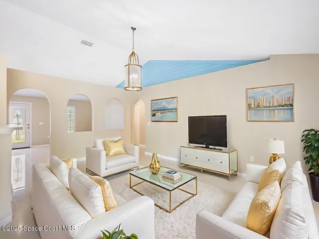 a living room with furniture a flat screen tv and a chandelier