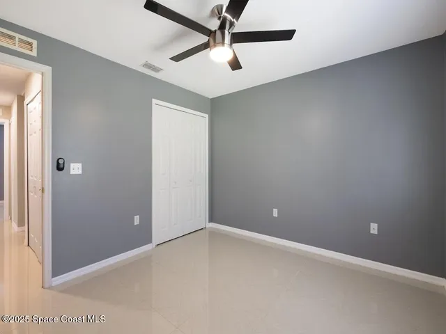 an empty room with ceiling fan and window