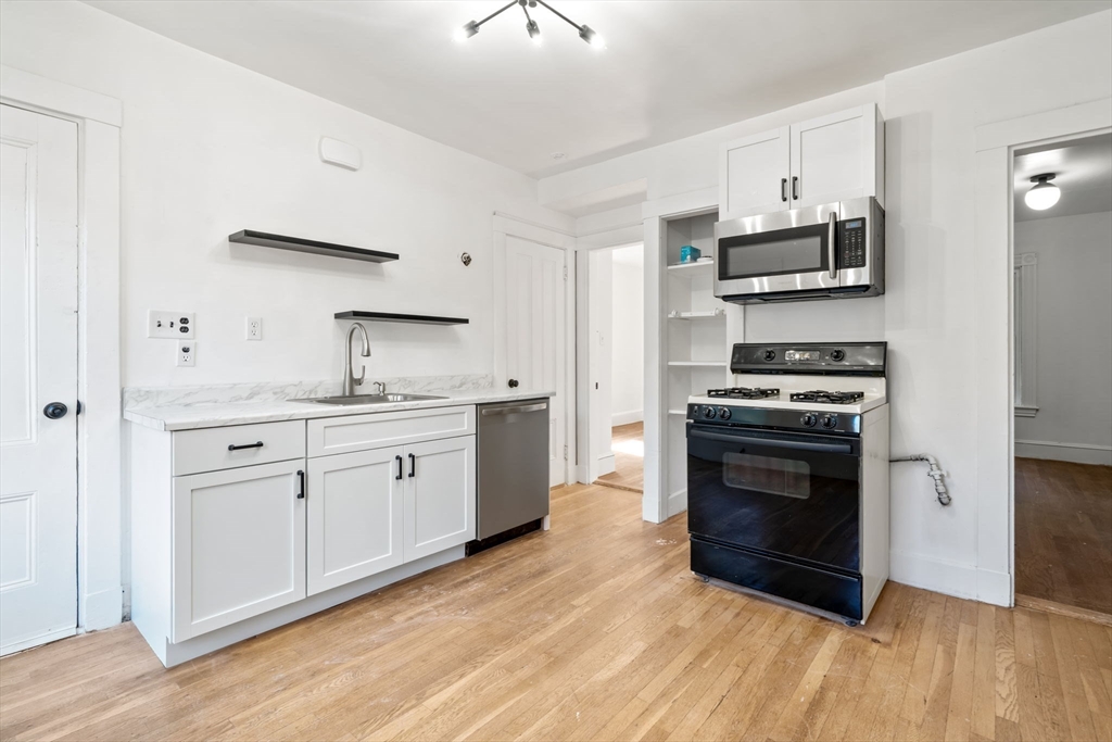 a kitchen with stainless steel appliances a stove a sink and white cabinets