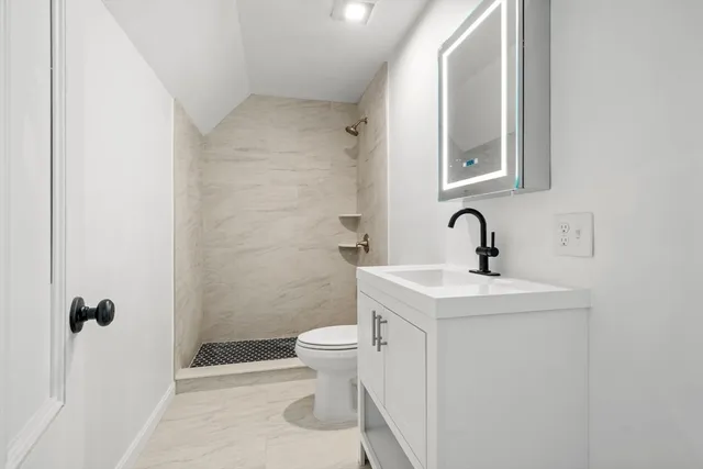 a bathroom with a sink a toilet a mirror and shower