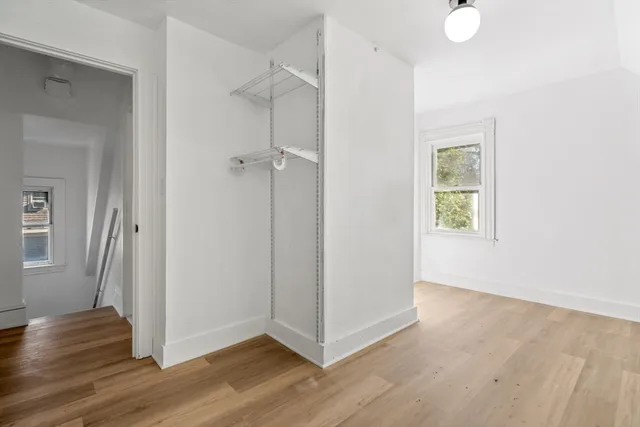 a view of a hallway with wooden floor and closet