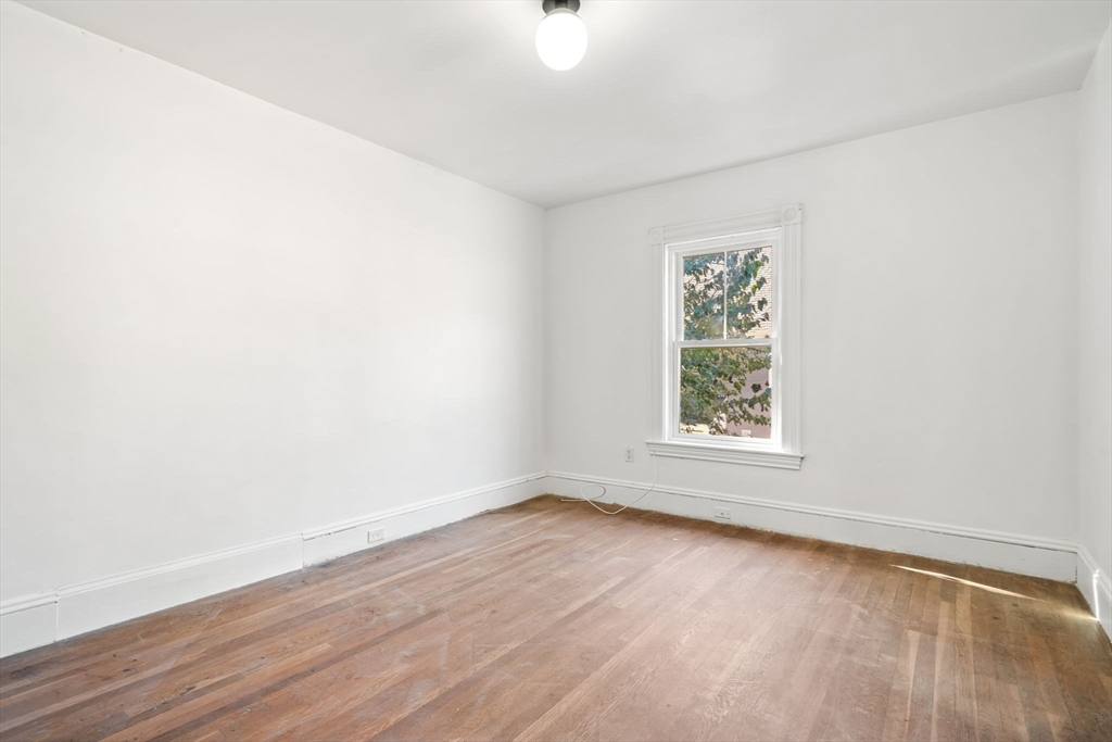 166 Elliot Street, Unit 2 Newton, MA 02464 - Photo 8 of 20 an empty room with wooden floor and windows