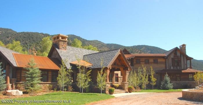 a view of a big house with a big yard and large trees
