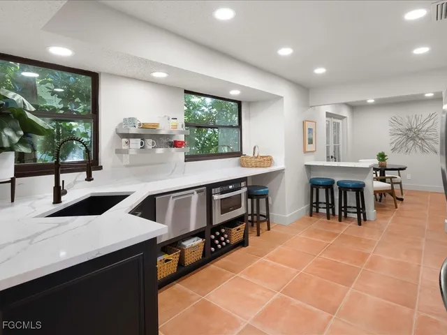 a kitchen with stainless steel appliances a sink a counter top space a large window and furniture