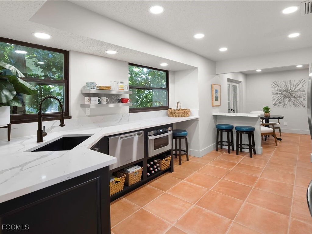 1046 Sperling Avenue Naples, FL 34103 - Photo 3 of 18 a kitchen with stainless steel appliances a sink a counter top space a large window and furniture