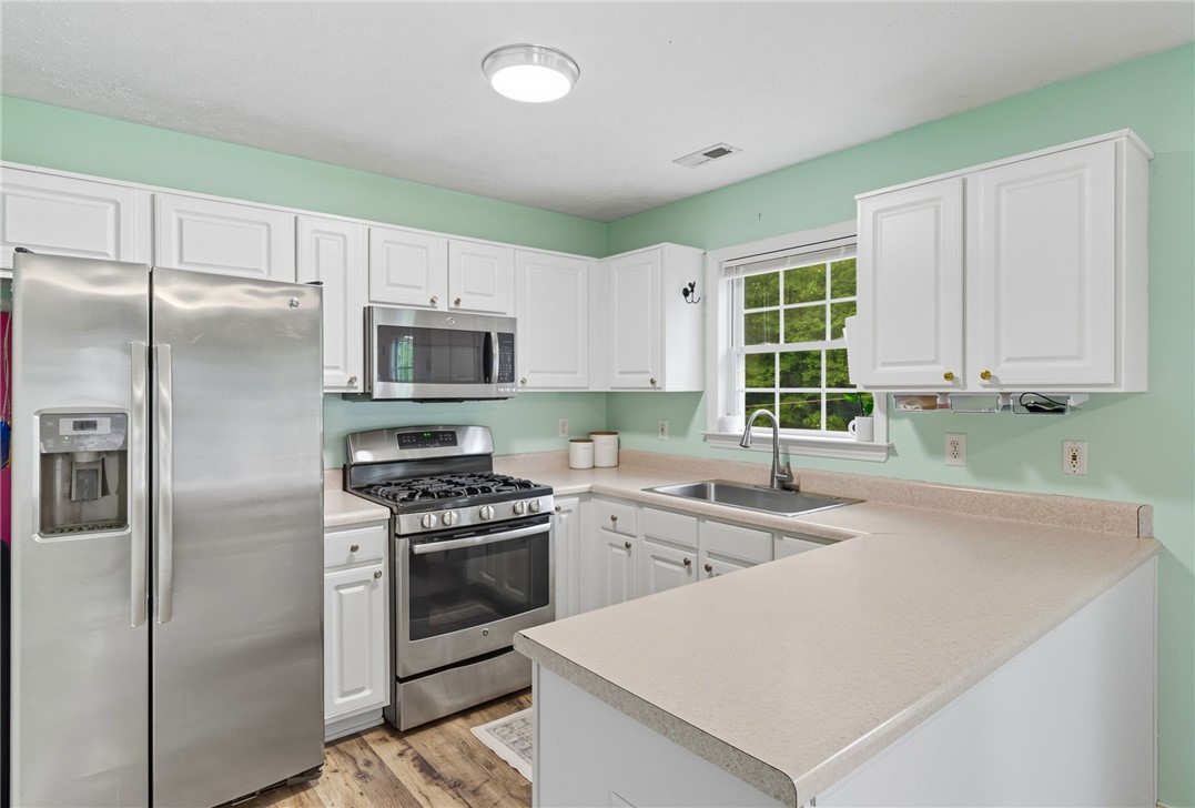 878 Salvia Road Newtown, VA 23126 - Photo 12 of 33 Kitchen featuring stainless steel appliances, light countertops, a peninsula, and white cabinets