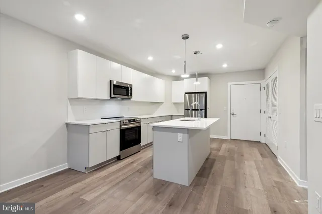 a kitchen with a sink wooden floor and stainless steel appliances