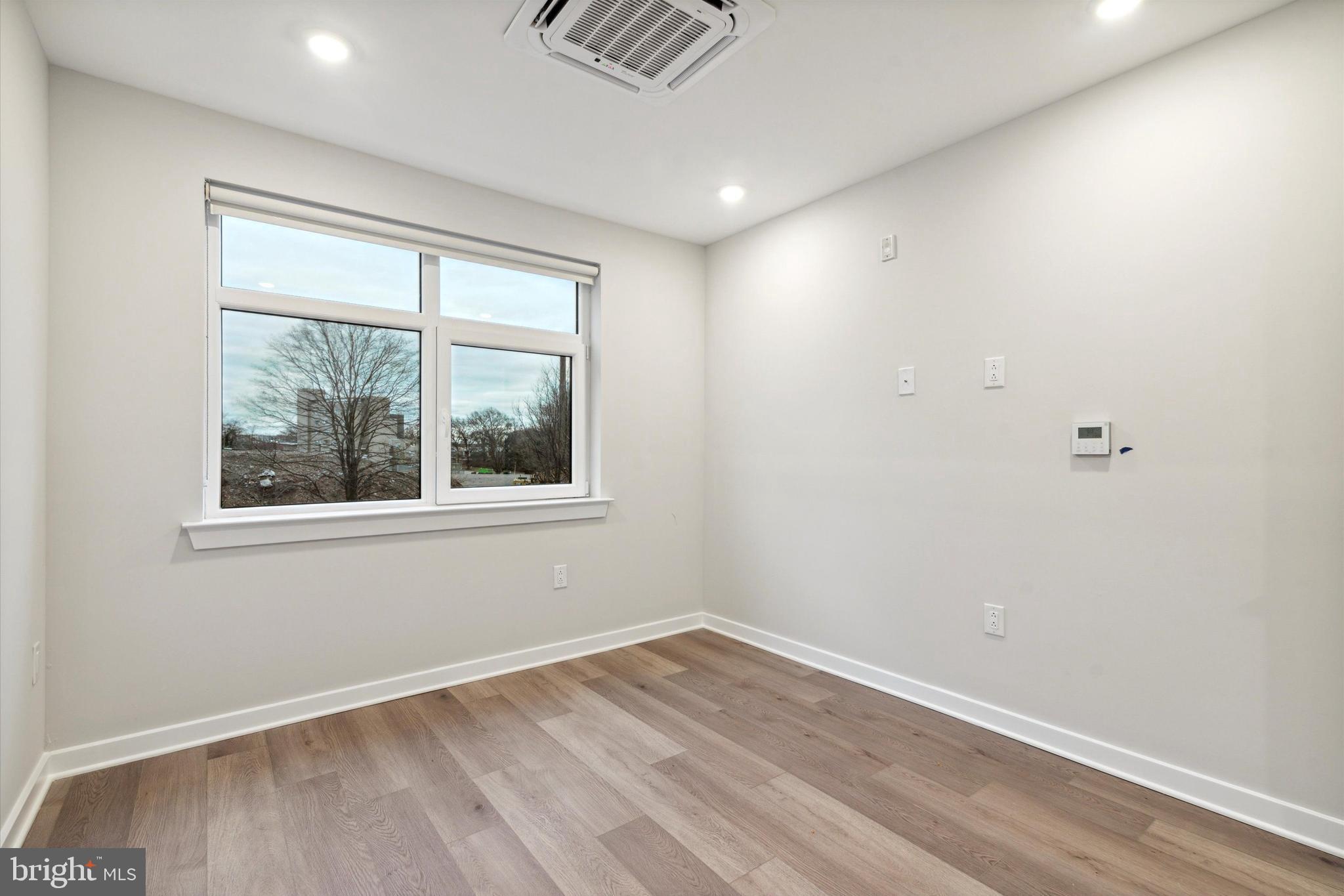 3449 Scotts Lane, Unit B303 Philadelphia, PA 19129 - Photo 8 of 9 an empty room with wooden floor and windows