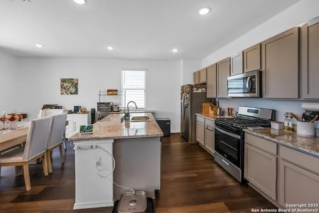 a kitchen with granite countertop a sink stove and refrigerator