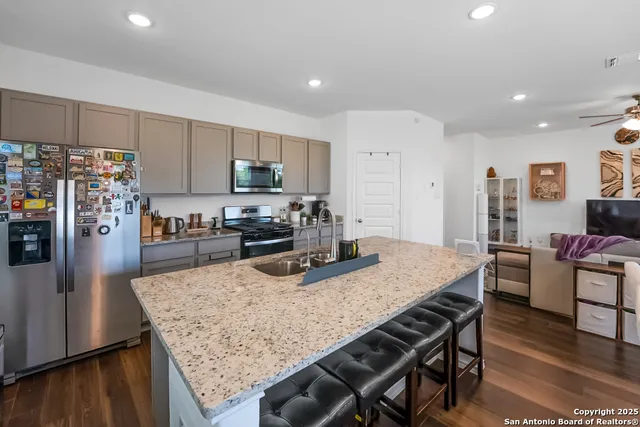 a kitchen with stainless steel appliances granite countertop a kitchen island hardwood floor and wooden cabinets