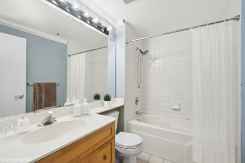 a bathroom with a sink a toilet a mirror a bathtub and shower