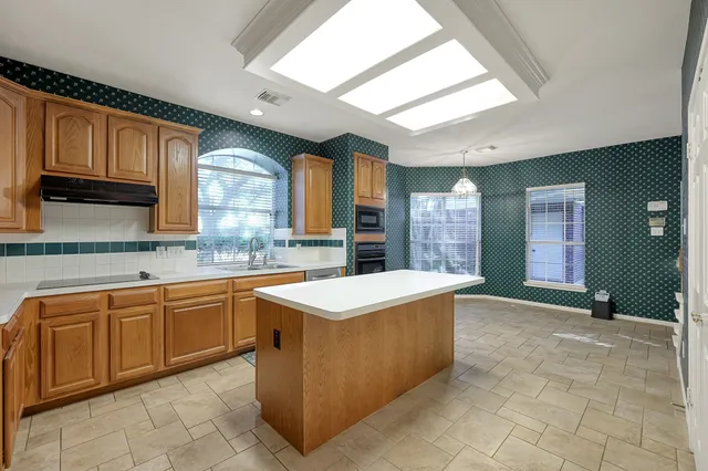 an empty room with windows and chandelier fan