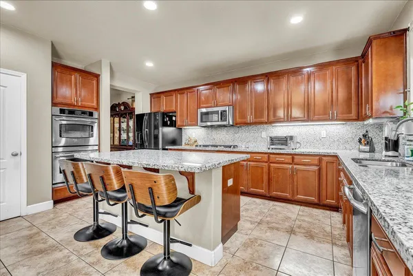 a kitchen with stainless steel appliances granite countertop a stove a sink dishwasher a refrigerator and cabinets with wooden floor