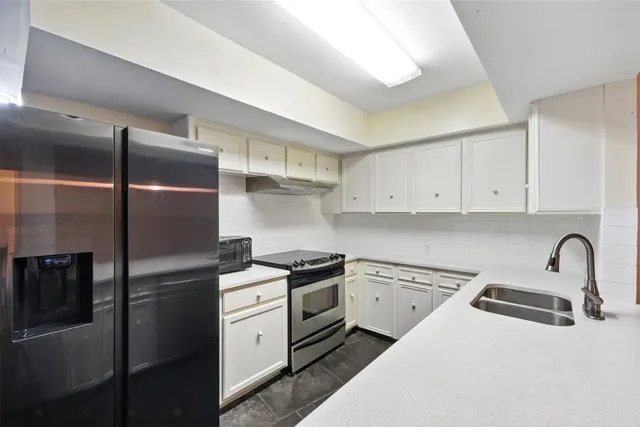 a kitchen with a refrigerator sink and cabinets