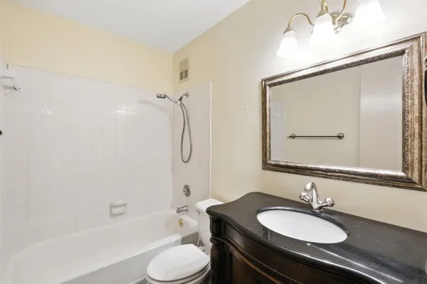 a bathroom with a granite countertop sink toilet a mirror and shower