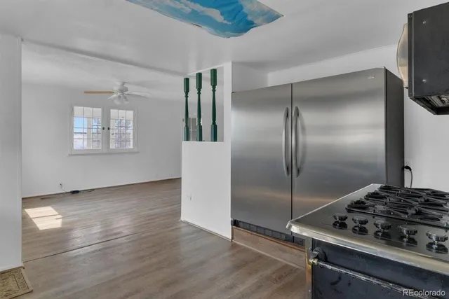 a kitchen with a refrigerator a stove and wooden floor