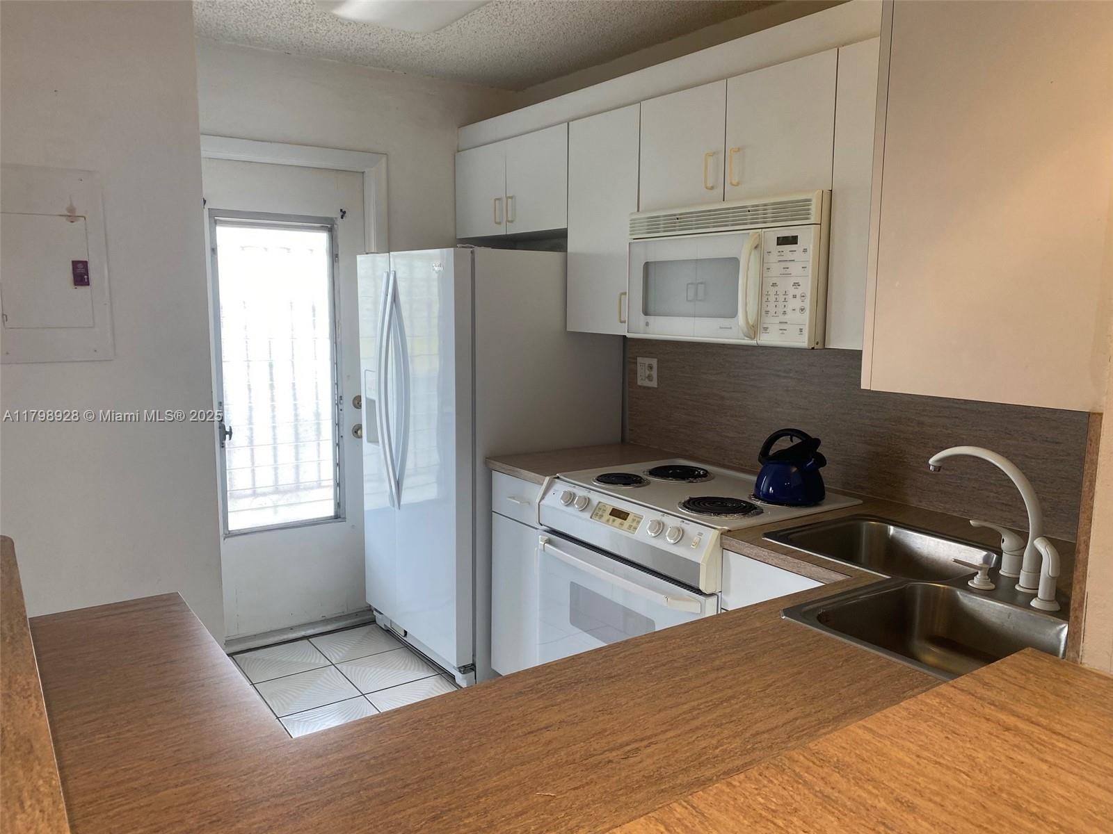 1400 Southwest 27th Avenue, Unit 202 Miami, FL 33145 - Photo 13 of 34 a kitchen with stainless steel appliances granite countertop a refrigerator a stove a sink and white cabinets with wooden floor