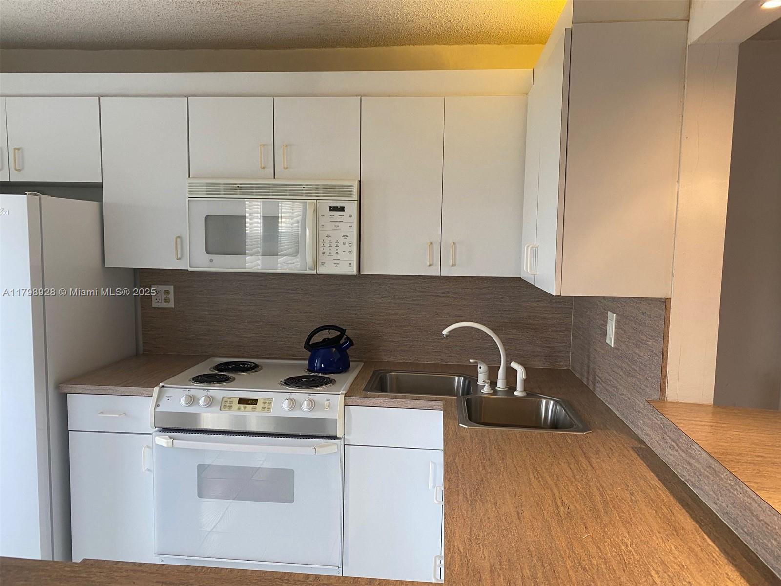 1400 Southwest 27th Avenue, Unit 202 Miami, FL 33145 - Photo 15 of 34 a kitchen with a sink a stove and cabinets