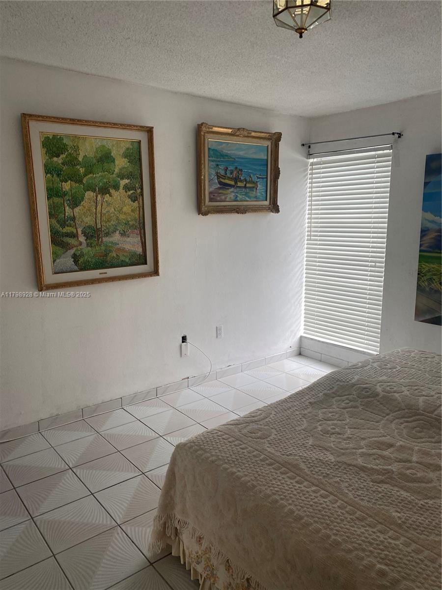 1400 Southwest 27th Avenue, Unit 202 Miami, FL 33145 - Photo 17 of 34 a bedroom with a bed and a painting on the wall