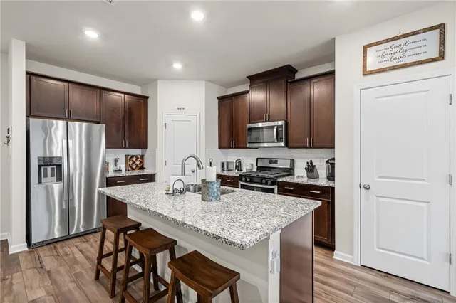 a kitchen with granite countertop a refrigerator a stove a sink cabinets and wooden floor