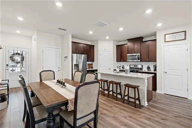 a kitchen with stainless steel appliances granite countertop a stove a refrigerator a kitchen island with a dining table and chairs