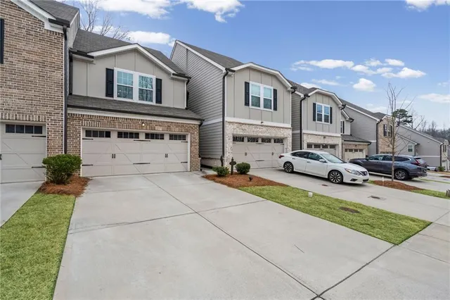 a view of a white house with a yard and table and chairs under an umbrella