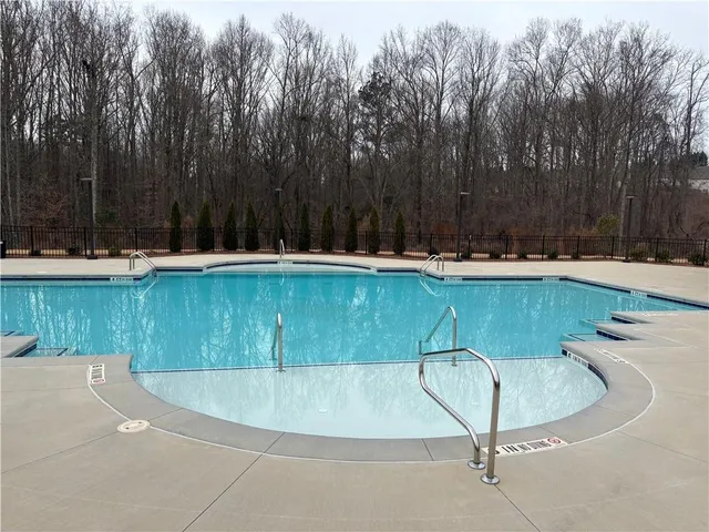 a view of a swimming pool with a yard and trees in the background