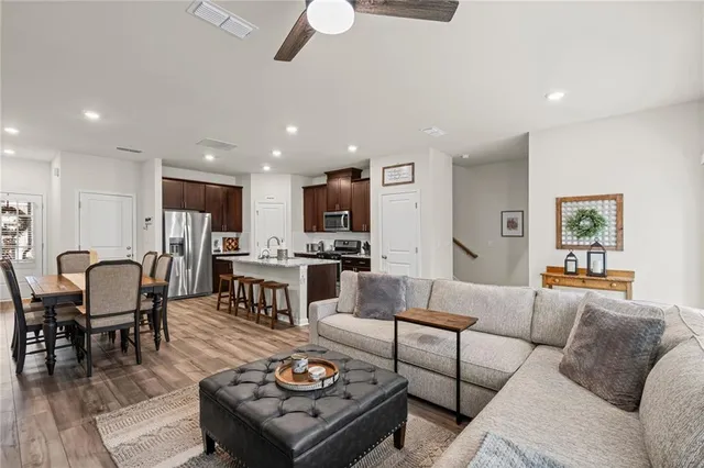 a living room with furniture kitchen view and a wooden floor