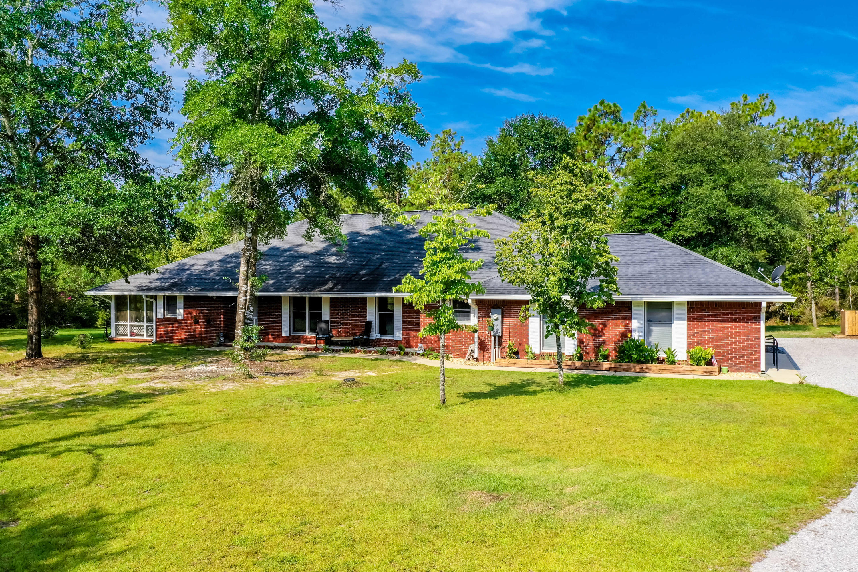 6116 Pine Ridge Lane Crestview, FL 32539 - Photo 1 of 45 a front view of a house with a garden and trees