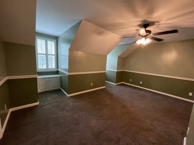 an empty room with windows and ceiling fan