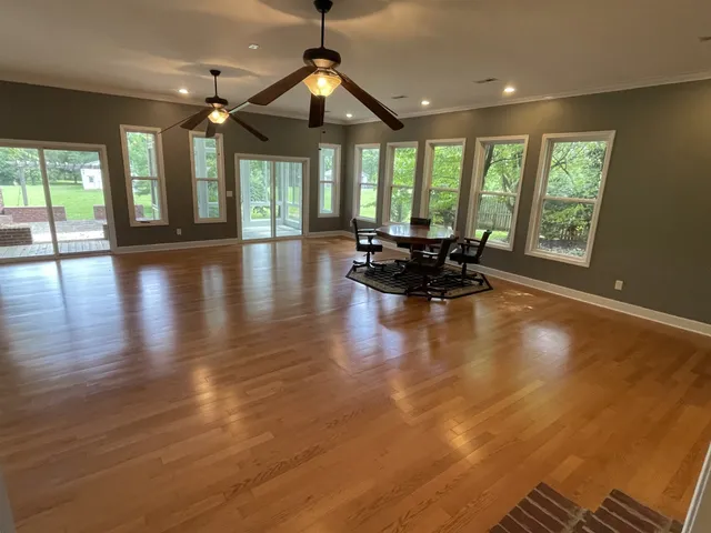 an empty room with large windows and wooden floor