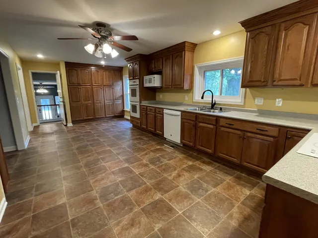 a large kitchen with stainless steel appliances a sink a stove a microwave a counter top space and cabinets