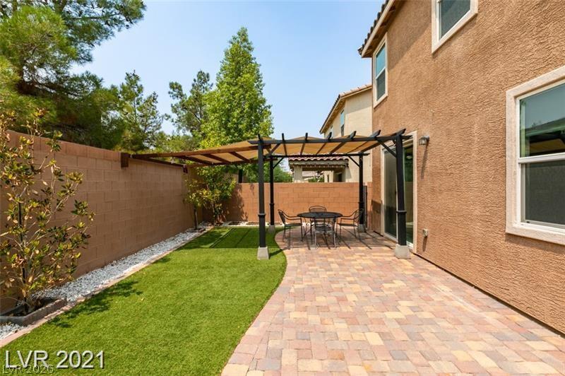 5475 Ordesa Valley Road Las Vegas, NV 89148 - Photo 7 of 35 An inviting backyard oasis offers a shaded patio, vibrant green lawn, and privacy wall.