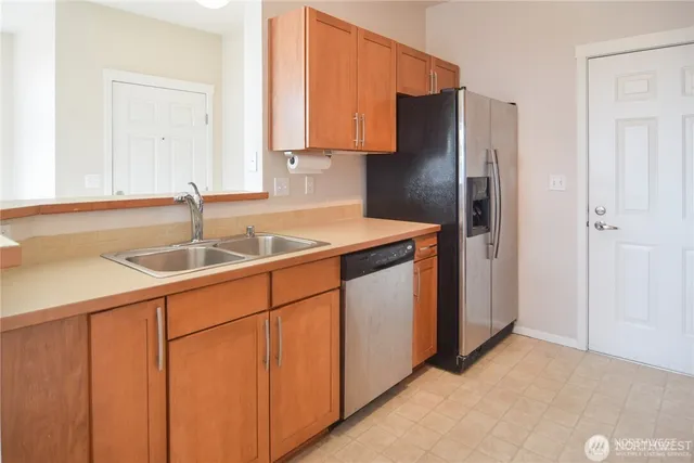 a kitchen with stainless steel appliances granite countertop a refrigerator a sink and white cabinets