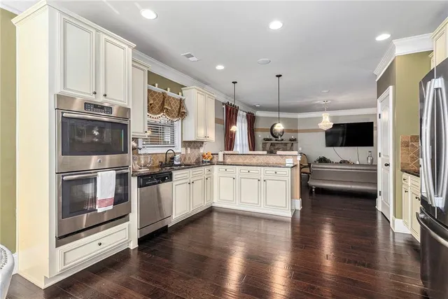 a kitchen with stainless steel appliances kitchen island granite countertop a stove a sink and white cabinets with wooden floor