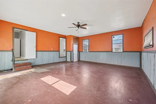 an empty room with windows and ceiling fan