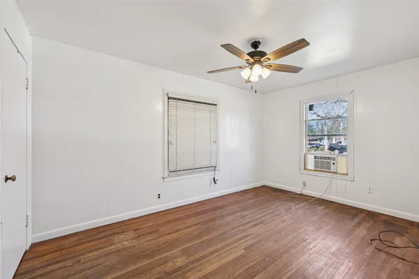 an empty room with wooden floor closet and ceiling fan