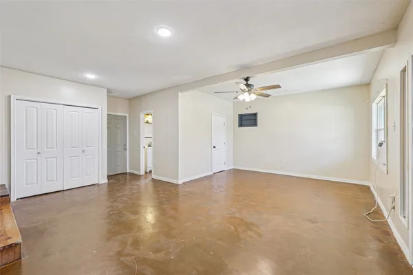 an empty room with a chandelier fan and closet area